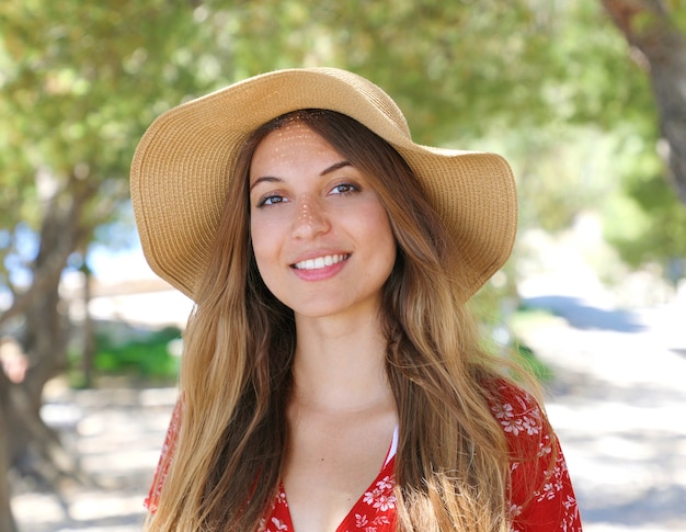 Mujer sonriente con sombrero y vestido rojo al aire libre