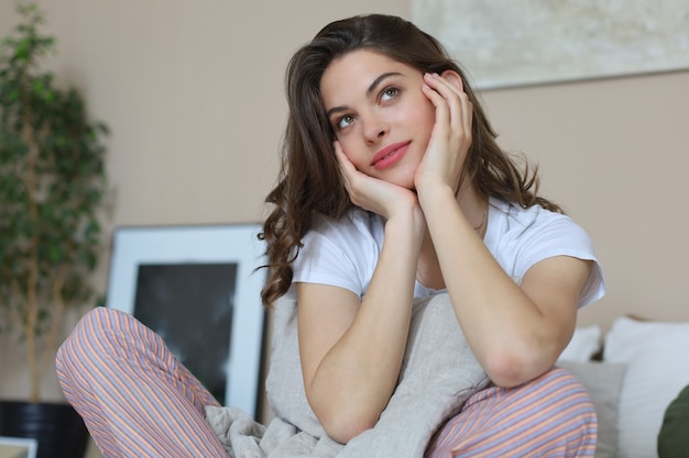 Mujer sonriente soñando despierto y relajándose en la cama.