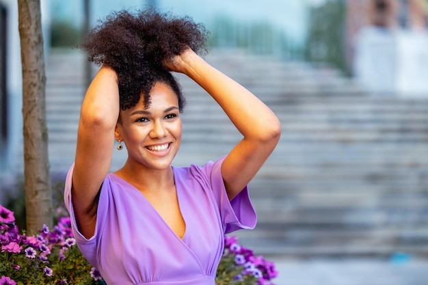 Mujer sonriente sosteniendo el cabello al aire libre