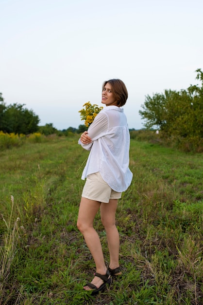 Foto mujer sonriente sosteniendo flores tiro completo