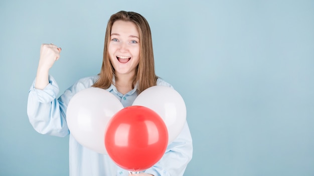 Mujer sonriente sosteniendo globo y mirando feliz