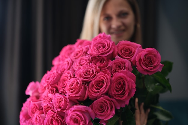 Mujer sonriente sosteniendo un gran ramo de rosas en sus manos