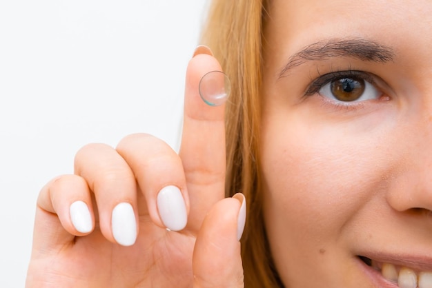 Foto mujer sonriente sosteniendo lentes de contacto en la punta de su dedo cerca de su cara