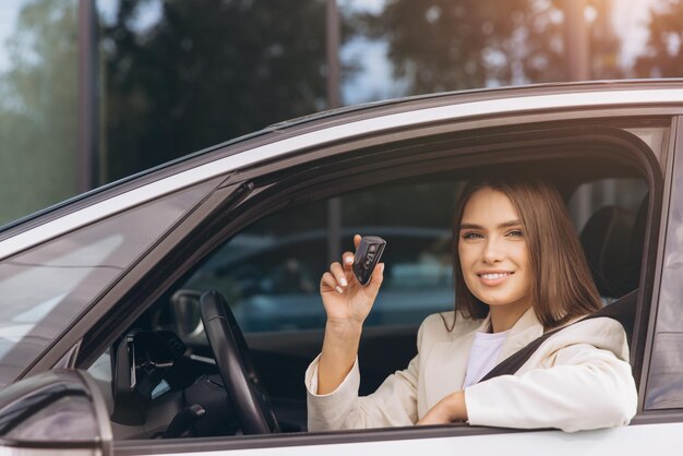 Mujer sonriente sosteniendo la llave del coche en un vehículo moderno