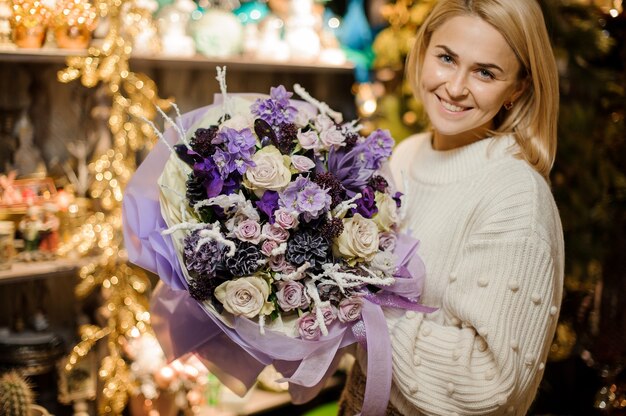 Mujer sonriente sosteniendo un ramo de flores de color púrpura y crema decorado