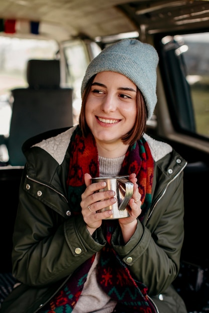 Mujer sonriente sosteniendo una taza de café en una camioneta