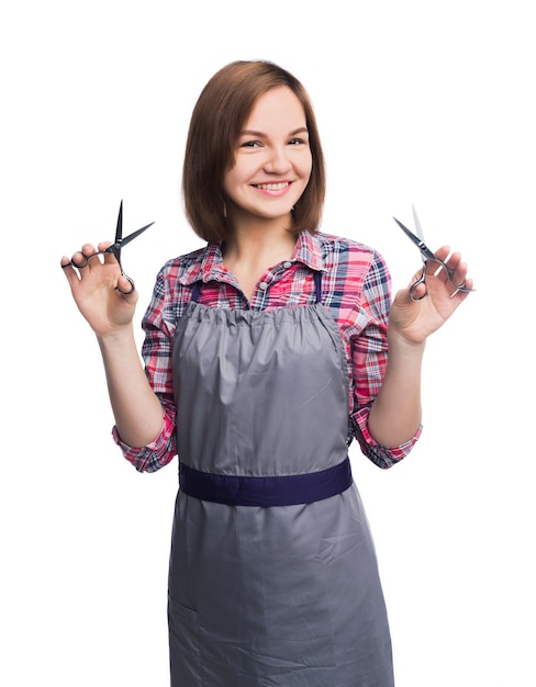 Mujer sonriente sosteniendo unas tijeras en el fondo blanco del estudio. Peluquería con equipo profesional, aislado