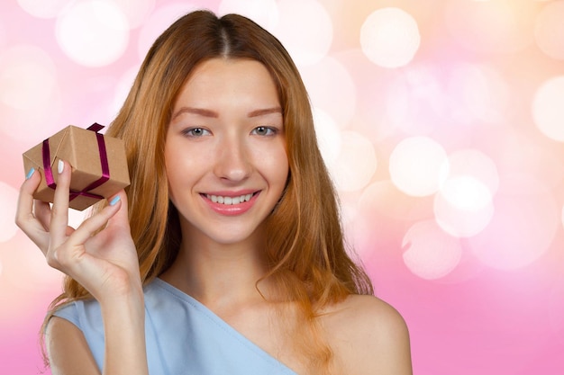 La mujer sonriente sostiene la caja de regalo