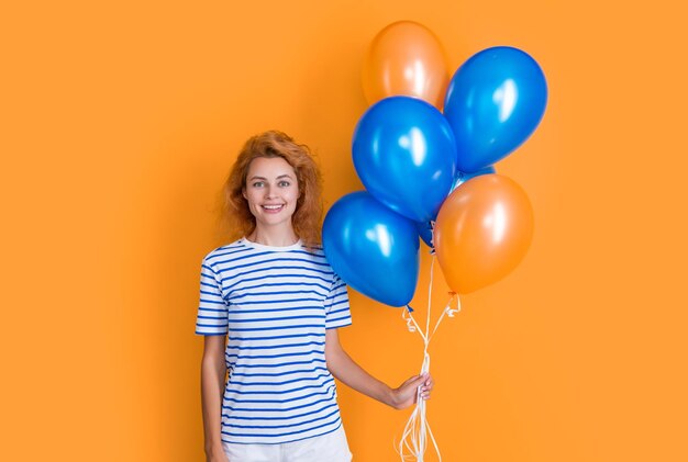 Mujer sonriente sostiene globos de fiesta en estudio mujer con globo para fiesta aislado en amarillo