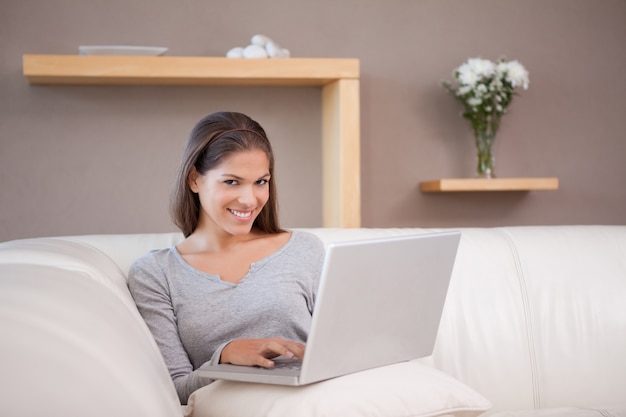 Mujer sonriente con su cuaderno en el sofá