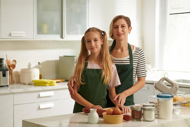 Mujer sonriente y su hija adolescente cocinando juntas la cena