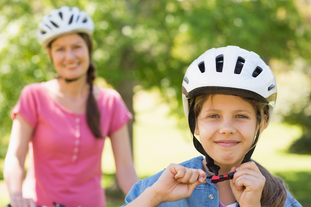 Mujer sonriente con su hija en bicicleta