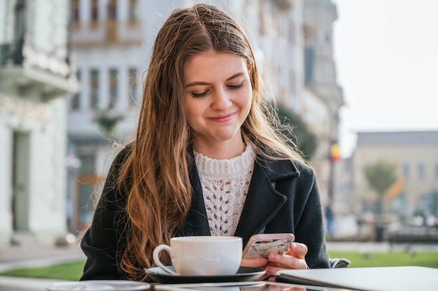 Mujer sonriente con su smartphone en un restaurante