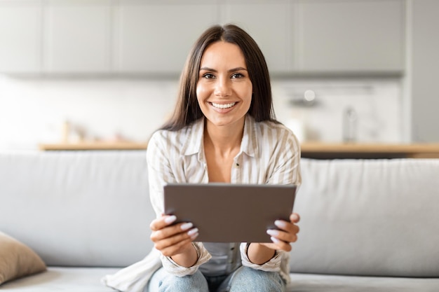 Mujer sonriente con una tableta en casa navegando por la web