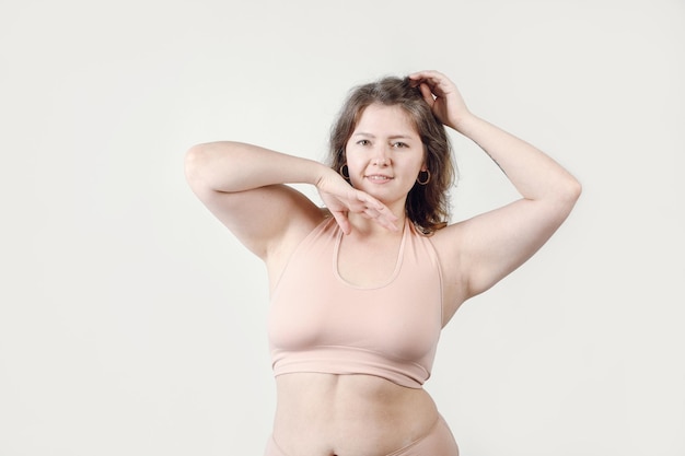 Una mujer sonriente de tallas grandes. Una chica regordeta sobre un fondo claro una actitud positiva hacia el cuerpo.