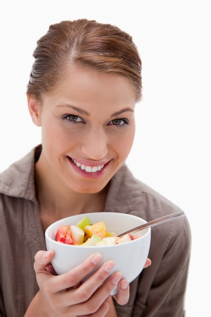 Mujer sonriente con tazón de ensalada de frutas