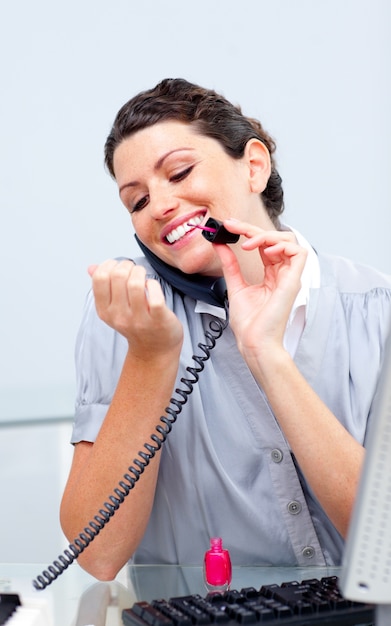 Mujer sonriente en el teléfono pintando sus uñas