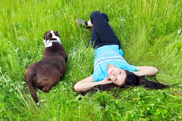 Mujer sonriente tirado en el pasto con perro