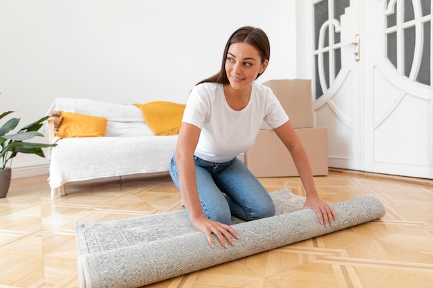 Mujer sonriente de tiro completo desplegando alfombra