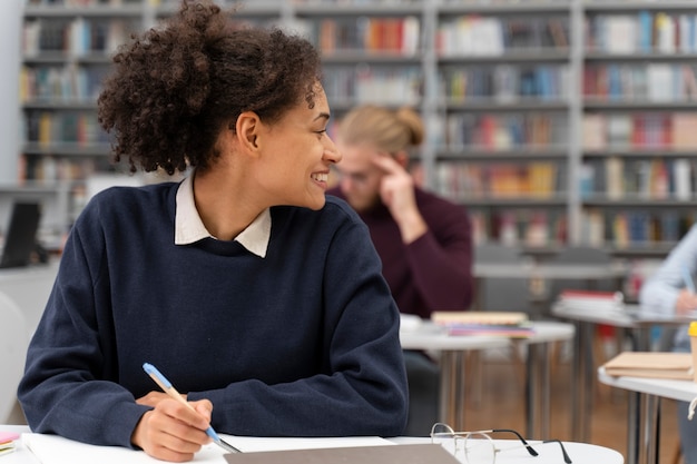 Foto mujer sonriente de tiro medio en biblioteca