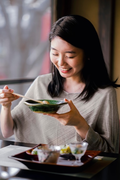 Mujer sonriente de tiro medio comiendo