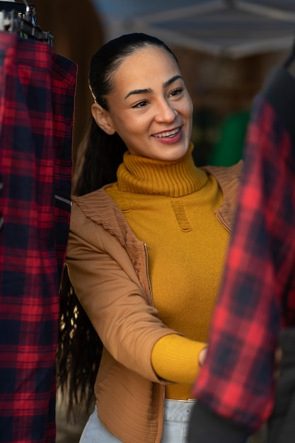 Mujer sonriente de tiro medio mirando ropa