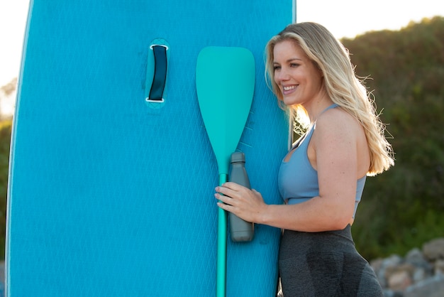 Foto mujer sonriente con tiro medio de paddleboard