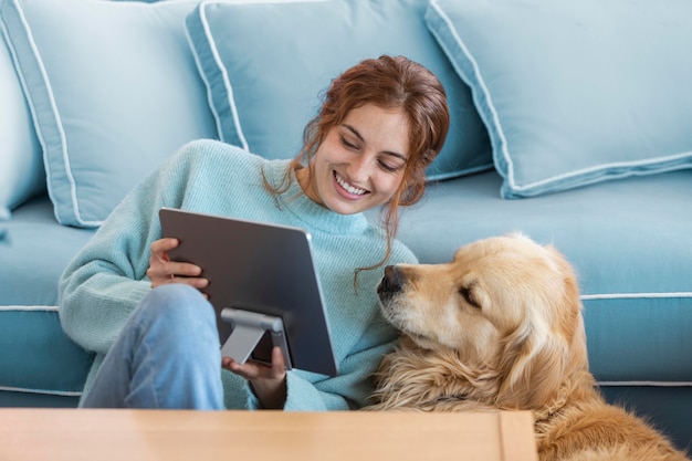 Foto mujer sonriente de tiro medio y perro con tableta