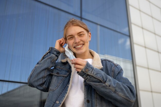 Mujer sonriente de tiro medio quitándose la máscara