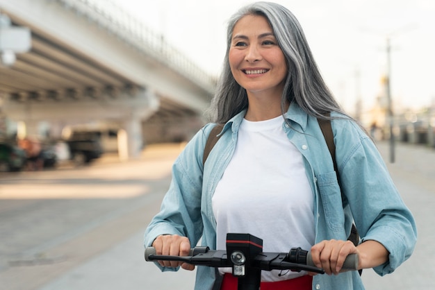 Mujer sonriente de tiro medio en scooter