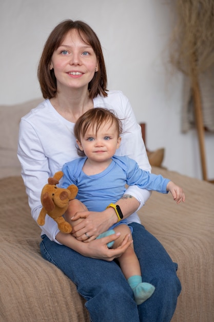 Mujer sonriente de tiro medio sosteniendo a su bebé