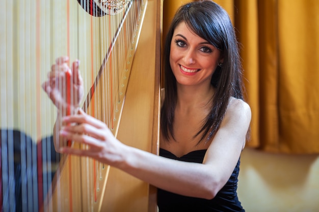 Mujer sonriente tocando un arpa