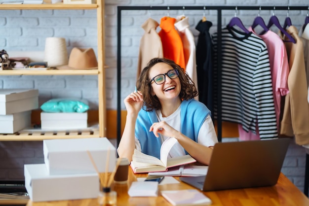 Foto la mujer sonriente toma notas de los pedidos con la computadora portátil. el propietario de dropshipping trabaja.