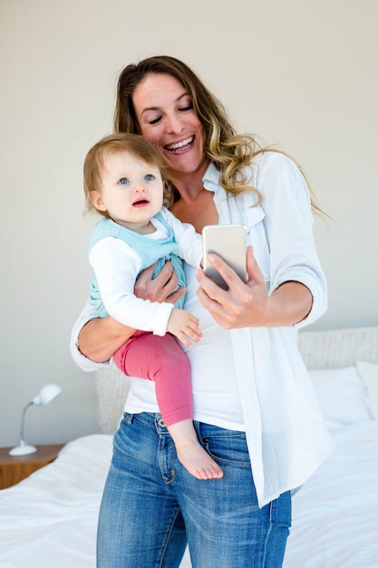 mujer sonriente tomando una selfie con un bebé en su teléfono móvil