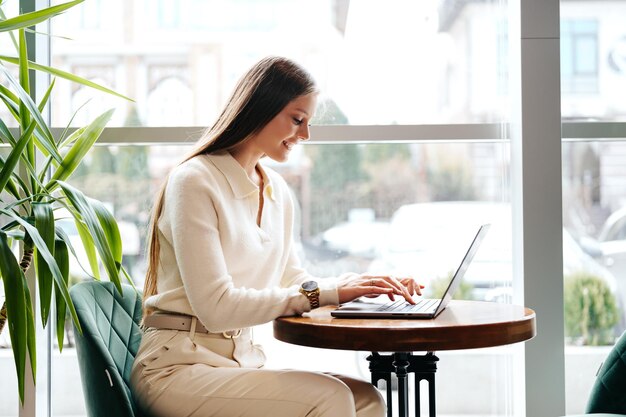 Mujer sonriente trabajando en una computadora portátil en una cafetería durante el día