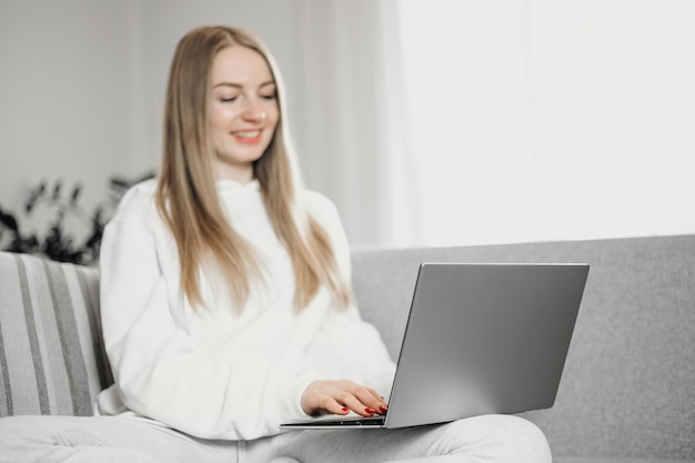 mujer sonriente y trabajando sentado en casa en el sofá con una computadora portátil