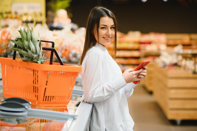 Mujer sonriente a través de teléfono móvil mientras compra en la tienda de compras