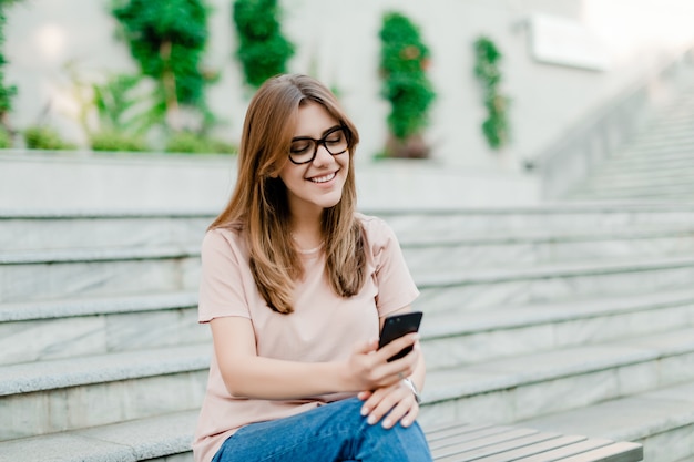 La mujer sonriente usa el teléfono al aire libre