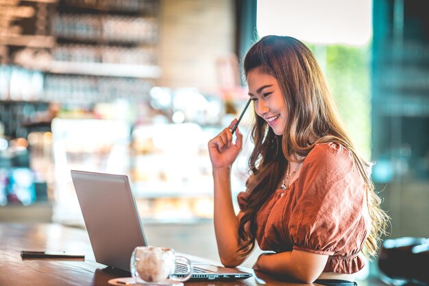 Foto mujer sonriente usando una computadora portátil en un café