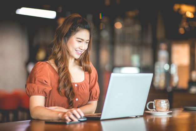 Mujer sonriente usando una computadora portátil en un café