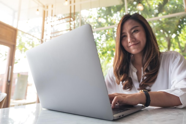 Foto mujer sonriente usando una computadora portátil en la mesa