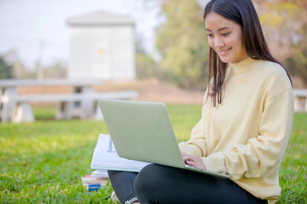 Mujer sonriente usando una computadora portátil mientras está sentada en el campo