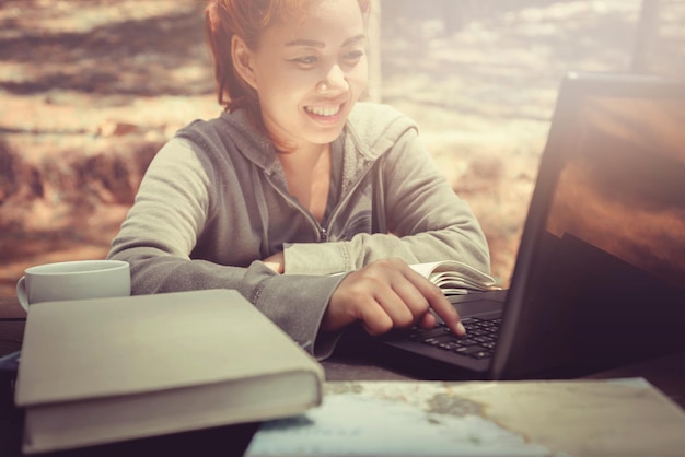 Mujer sonriente usando una computadora portátil mientras está sentada en la mesa al aire libre