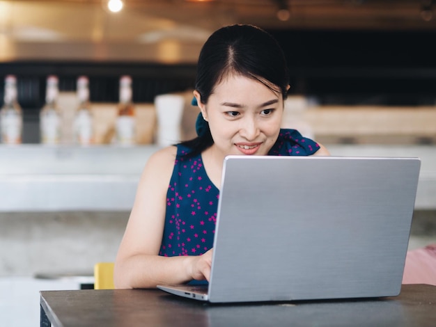 Mujer sonriente usando una computadora portátil mientras está sentada en la mesa