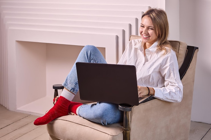 Foto mujer sonriente usando una computadora portátil sentada en el sofá en casa