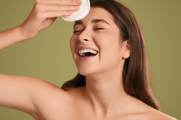 Mujer sonriente usando disco cosmético en la cara