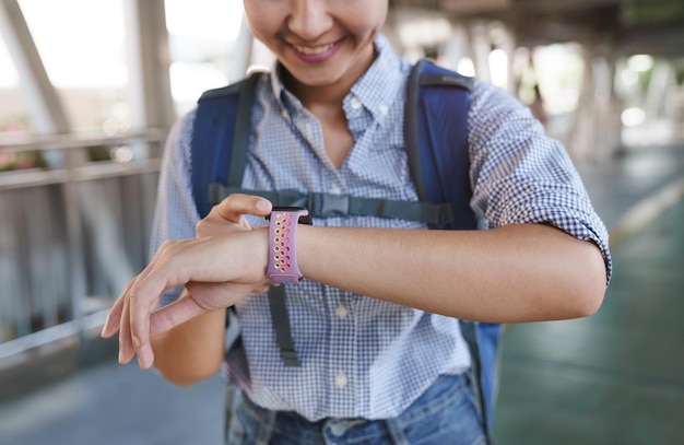 Foto mujer sonriente usando smartwatch y caminando en la ciudad