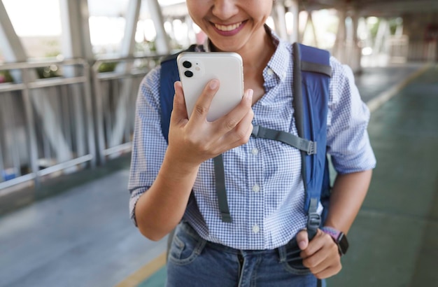 Mujer sonriente usando teléfono y caminando en la ciudad