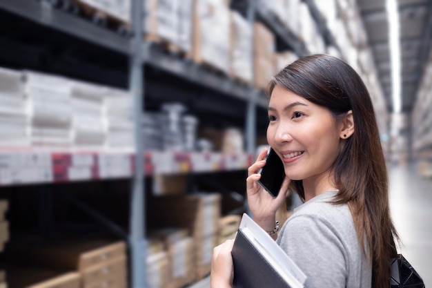 Foto mujer sonriente usando el teléfono mientras está de pie en el almacén