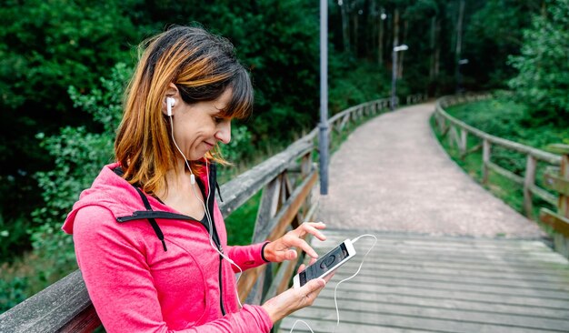 Foto mujer sonriente usando el teléfono mientras está de pie en la pasarela